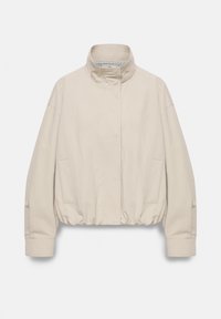 Veste beige crème avec col montant, manches longues, ourlet élastique et poches latérales, présentée sur un fond clair uni.