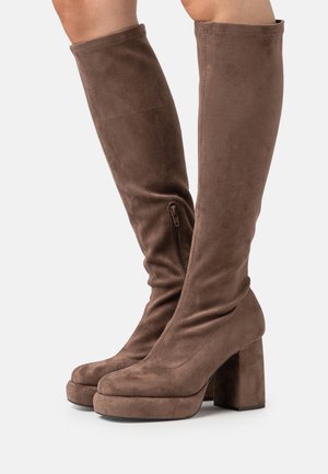 Bottes hauteur genou en daim marron avec un talon bloc épais, un bout arrondi, une fermeture éclair latérale et une texture lisse.