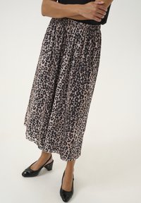 Leopardprint midi-nederdel i beige og sort, letvægtsstof, elastisk talje, med en flydende silhuet og nederdelens kant. Sorte hæle.