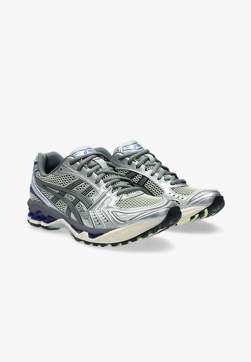 Un paio di scarpe da corsa Asics grigie e argento con sovrapposizioni in rete e sintetico, strisce nere del logo e suole ammortizzate su uno sfondo bianco.