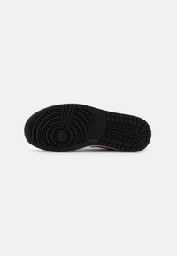 Suela de zapato de goma negra con patrones de banda de rodadura circulares y lineales, que presenta el logotipo de Nike y acentos texturizados en toda su superficie.