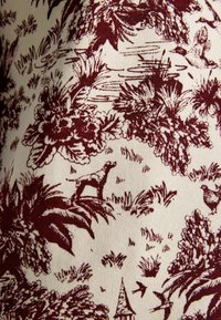 Bordová a krémová látka s pastelovou scénou zobrazenou zvieratami a rastlinami; podrobné vzory stromov, trávy a vodných prvkov.