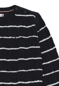Maglione a maglia cable blu navy con strisce orizzontali bianche, due bottoni neri sulla spalla e un piccolo logo rosso, bianco e blu sul petto.
