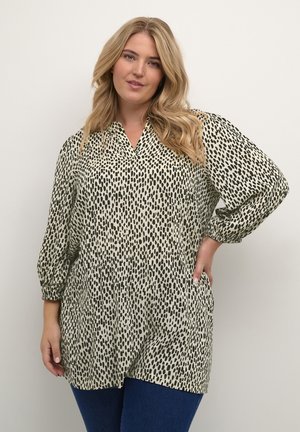Blusa in beige chiaro con motivo a pois astratti neri, scollatura a V, maniche lunghe a sbuffo e vestibilità comoda. Tessuto liscio con leggera lucentezza.