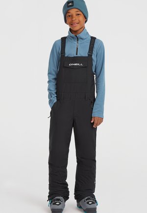 Zwarte sneeuwoverall met verstelbare banden en een voorzak, gecombineerd met een lichtblauwe fleece met rits en een bijpassende muts.