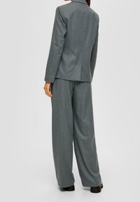 Šedý blejzr a kalhoty s širokými nohavicemi, vyrobené z texturované tkaniny. Obsahuje dobře padnoucí střih a jemný rozparek na zadní straně pro zvýšení pohodlí.
