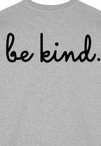 Szürke póló pulóver rövid ujjakkal, hátulján nagy fekete, írott betűkkel "légy kedves" felirattal. Puha tapintású, laza dizájn.