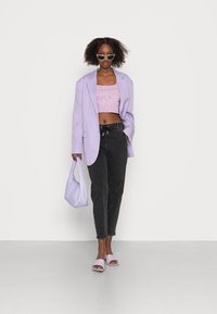 Lavender oversized blazer, pink ribbed crop top, black tapered jeans, lavender handbag, and matching mules with open toes, all on a white background.