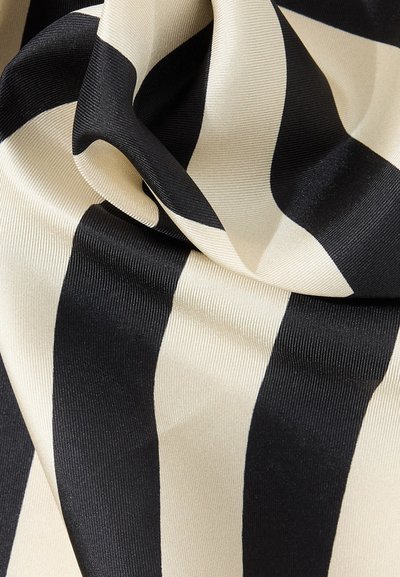 Ύφασμα με κάθετες ασπρόμαυρες ρίγες, με λεία, γυαλιστερή υφή, διατεταγμένο σε απαλές πτυχώσεις.