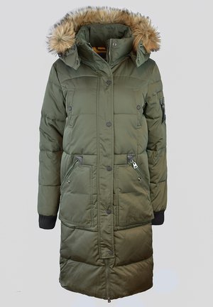 Parka matelassée vert olive avec une capuche bordée de fourrure, des boutons-pression, des poches latérales zippées, des poignets côtelés et une silhouette arrivant au genou.
