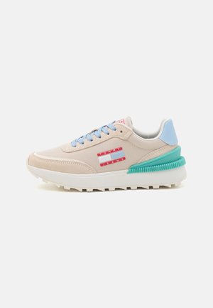 Beżowe i jasnoniebieskie buty sportowe z turkusowym detalem na pięcie, jasnoniebieskimi sznurowadłami oraz czerwono-białym logo Tommy Jeans po boku.