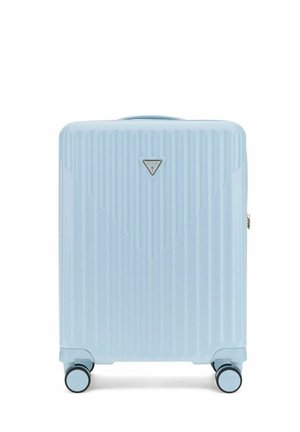 Valise rigide bleu clair avec des rainures verticales, quatre roues pivotantes et un petit logo triangulaire Guess à l'avant.