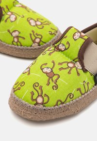 Gröna espadrillos i tyg med ett mönster av apor, bruna detaljer, elastiska sidopaneler och texturerade jutesulor.