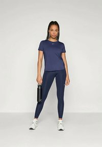 Navy athletic t-shirt and leggings made from lightweight material. Features a small logo on the chest and a water bottle in hand.