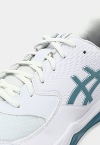 Hvit atletisk sko med blå detaljer, teksturert syntetisk overdel, meshdeler og hvite snørebånd. Inkluderer tonalt sømdetalj.