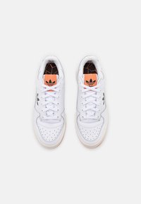 Vita sneakers med en slät läderöverdel med perforerade detaljer, orange accenter och svart logotyp på sidan. Gummisulor.