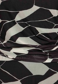 Schwarz-weiß gemusteter Stoff mit unregelmäßigen, abstrakten Formen. Die Textur ist glatt, mit einem leichten Glanz und einem drapieren Erscheinungsbild.