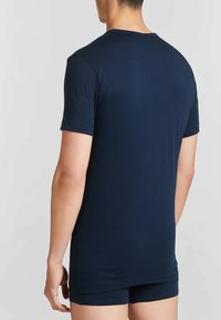 T-shirt blu navy a maniche corte realizzato in tessuto morbido, con scollatura rotonda e vestibilità aderente, vista da dietro con dettagli minimi.