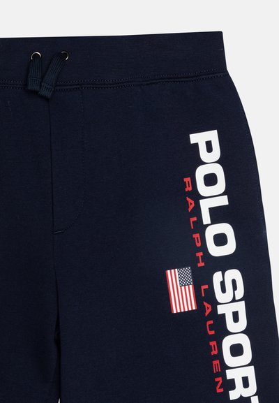 Marina blå sweatpants i bomull, med vit "POLO SPORT" text och en liten amerikansk flagg grafik på vänster ben. Dragsko i midjan.
