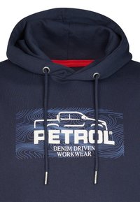 Námornícky mikina s prednou grafikou, na ktorej je slovo "PETROL" a "DENIM DRIVEN WORKWEAR." Obsahuje kapucňu so šnúrkou a strieborné očká.
