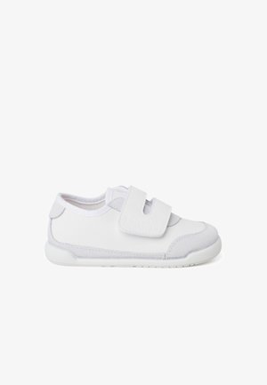 Basket blanche avec une sangle velcro, en cuir lisse et en suède, à bout rond et semelle en caoutchouc texturée pour une bonne adhérence.