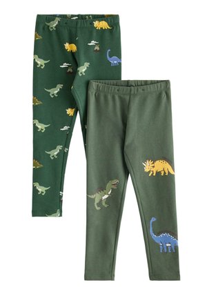 Smilende ung dreng iført grøn dinosaur-tema langærmet trøje og matchende leggings med forskellige farverige dinosaurtryk, hvide sko.