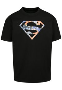 Black cotton t-shirt featuring a large Superman logo with a floral pattern in blue, orange, and white, set against a black background.
