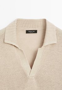 Bežový pletený svetr s výstřihem do V a ribbeným límcem. Má jemnou texturu a je vyroben z lehkého materiálu. Značka: Massimo Dutti.