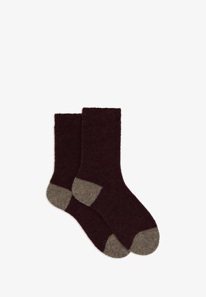 Burgundy socks with a soft texture feature a contrasting light brown heel and toe. They have a mid-calf length and a seamless design.