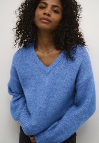 V-hals truien in zachte blauwe knit, met oversized mouwen en een relaxed fit. Gestructureerde stof met geribbelde boorden en zoom.