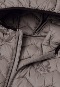 Leichte, gesteppte Jacke in gedecktem Grau. Verfügt über einen Reißverschluss, eine Kapuze und einen Logo-Akzent. Glatte Oberfläche mit sechseckigem Muster.