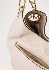 Rosa Lederhandtasche mit strukturiertem Finish, ausgestattet mit einem goldenen Reißverschluss, goldenen Beschlägen und einem Logo-Akzent im Inneren.