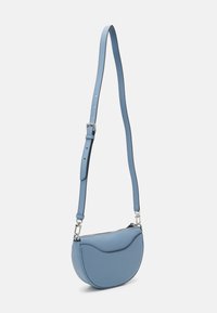 Sac bandoulière en cuir bleu clair, de forme incurvée, avec une sangle réglable et des détails en métal argenté. Texture lisse avec des coutures discrètes.