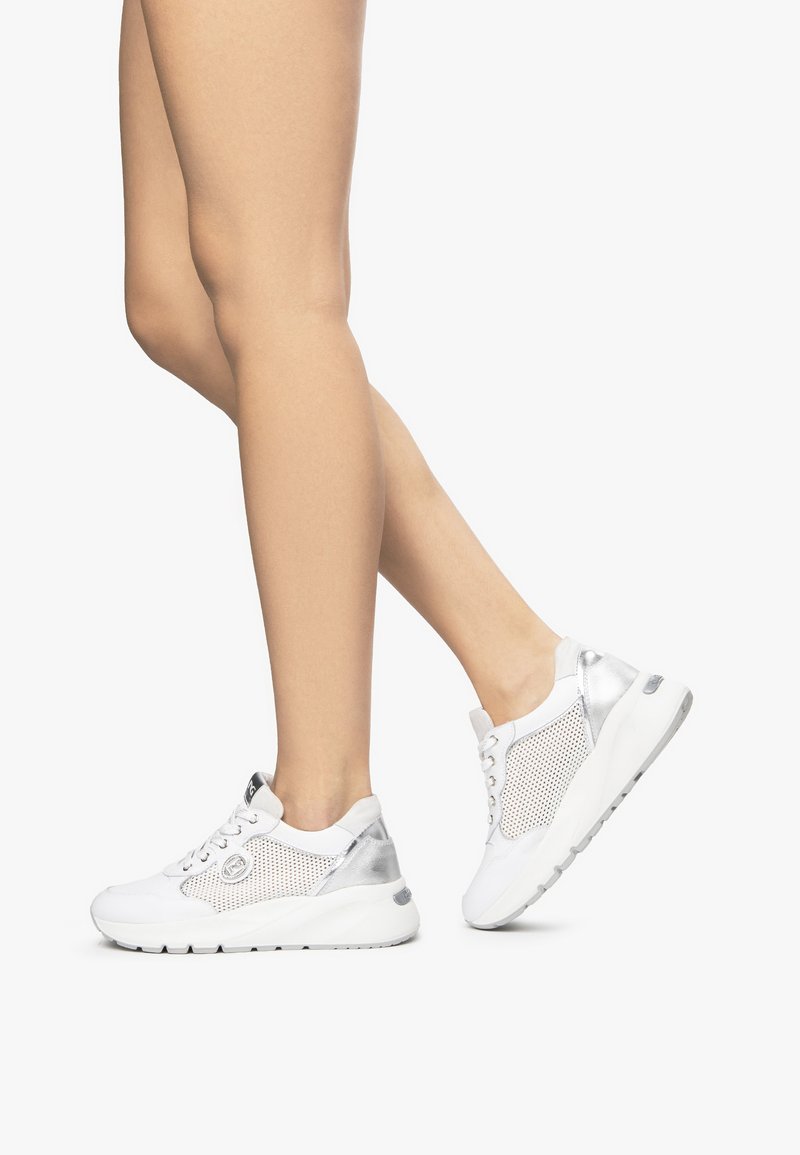 Weiße Sportsneaker mit silbernen Akzenten, Mesh-Material, abgerundete Zehenpartie und strukturierte Sohle. Schnürschuh-Design mit markantem Markenlogo.