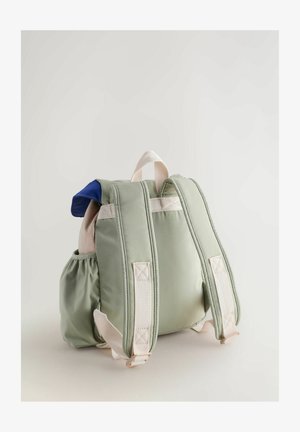 Zöld párnázott hátizsák kék kiegészítőkkel, oldalsó zsebbel, állítható pántokkal és egy kis felső fogantyúval. Puha szövet, sima tapintással.