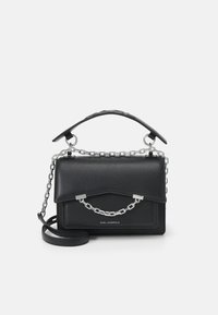 Sac à main en cuir noir avec des accents de chaîne en argent. Design structuré, anse supérieure et bandoulière ajustable. Texture lisse et logo minimal.