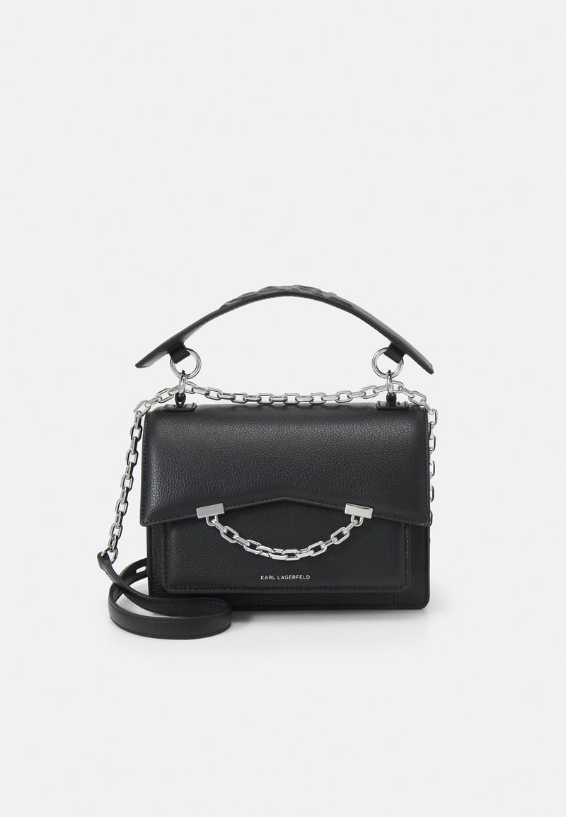 Sac à main en cuir noir avec des accents de chaîne en argent. Design structuré, anse supérieure et bandoulière ajustable. Texture lisse et logo minimal.