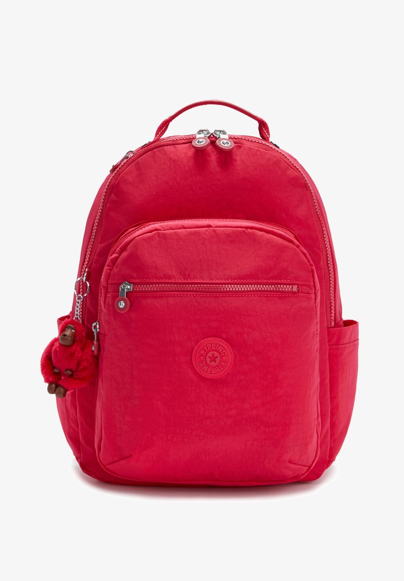 Zaino in nylon rosso con tasca frontale con zip, logo circolare e portachiavi a forma di scimmia. Presenta spallacci imbottiti e una superficie testurizzata.