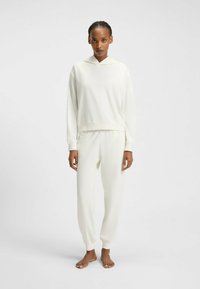 Ensemble de vêtements d'intérieur de couleur crème comprenant un pull à capuche et un pantalon de jogging fuselé. Tissu doux et lisse avec des poignets et une taille côtelés.