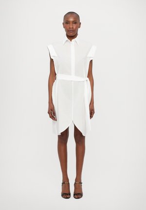 Witte jurk met korte mouwen, knoopsluiting aan de voorkant, ceintuur in de taille en asymmetrische zoom. Gemaakt van lichtgewicht, doorzichtig materiaal.