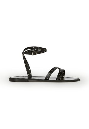 Czarna płaska sandałka z cienkimi paskami ozdobionymi srebrnymi oczkami, jednym wokół kostki z klamrą oraz dwoma krzyżującymi się na palcach.