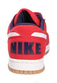 Zapatilla roja con parte superior de textil y acentos en azul marino. Presenta grandes letras azules "NIKE" en el talón y una suela de goma.