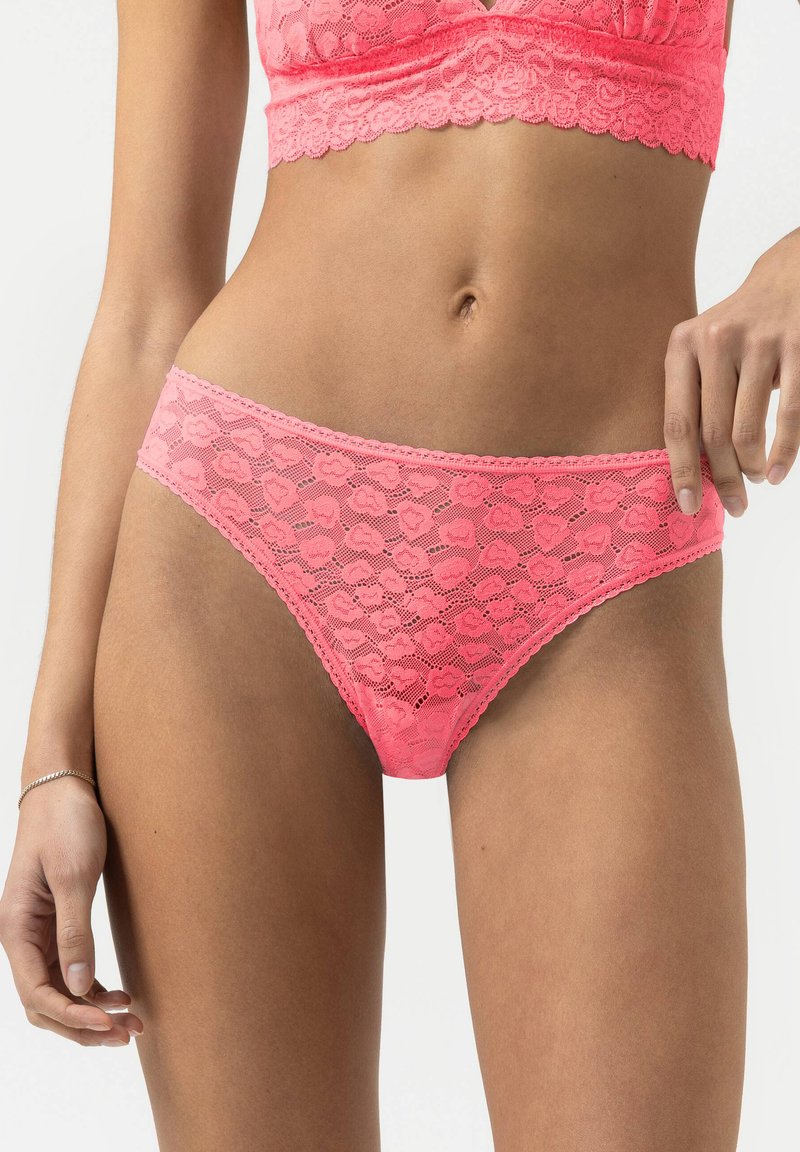 Rosa spetsunderkläder med hjärtmönster, med en stretchig midja och vågiga kanter, del av ett matchande set med en bralette.