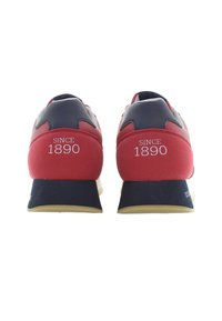 Czerwone i granatowe buty sportowe z teksturowanej tkaniny, z wyściełanym kołnierzem i gumową podeszwą. Na tyle oznaczenie "OD 1890 ROKU".