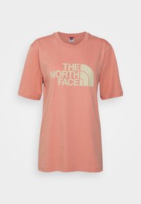 Kortärmad, korallfärgad bomulls-T-shirt med rund halsringning och tydlig vit "THE NORTH FACE"-logotyp på framsidan. Slät textur.