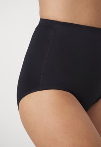 Korkeavyötäröiset mustat bikinit, jotka on valmistettu sileästä ja joustavasta kankaasta. Niissä on puhtaat saumat ja klassinen muotoilu mukavuutta ja hyvää istuvuutta varten.