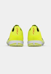 Φωτεινά κίτρινα αθλητικά παπούτσια με κομψό σχεδιασμό, με λευκές σόλες και μαύρες λεπτομέρειες, με την ένδειξη "F50" στη φτέρνα.