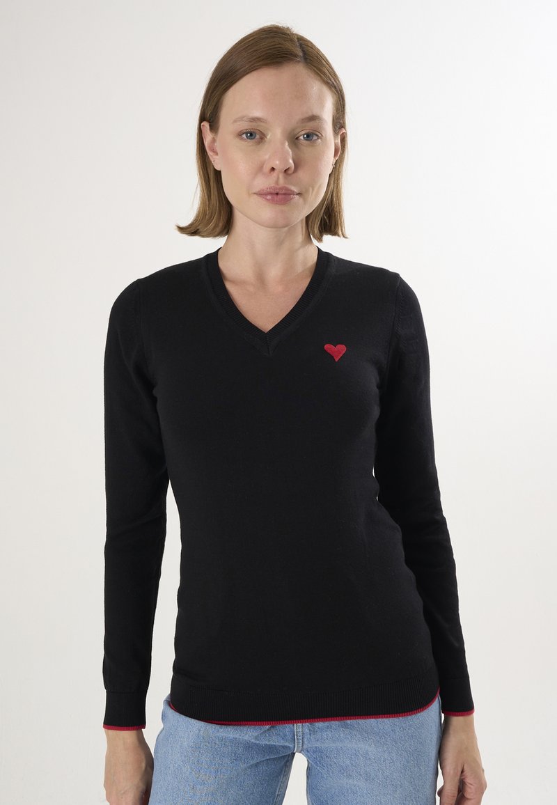 Schwarzer Pullover mit langen Ärmeln, V-Ausschnitt, roter Herzbestickung auf der Brust und kontrastierendem roten Saum an den Bündchen und am unteren Saum.