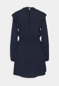 Mörkblå klänning med långa ärmar, volangdetaljer på axlarna, elastisk midja och lager av peplumkant. Stängs med en nacke knytning bak.