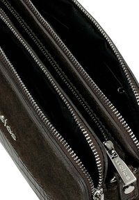 Brązowy skórzany portfel z zamszowymi i wzorzystymi akcentami. Posiada wiele przegrody z metalowymi suwakami w kolorze srebrnym oraz czarną podszewką.